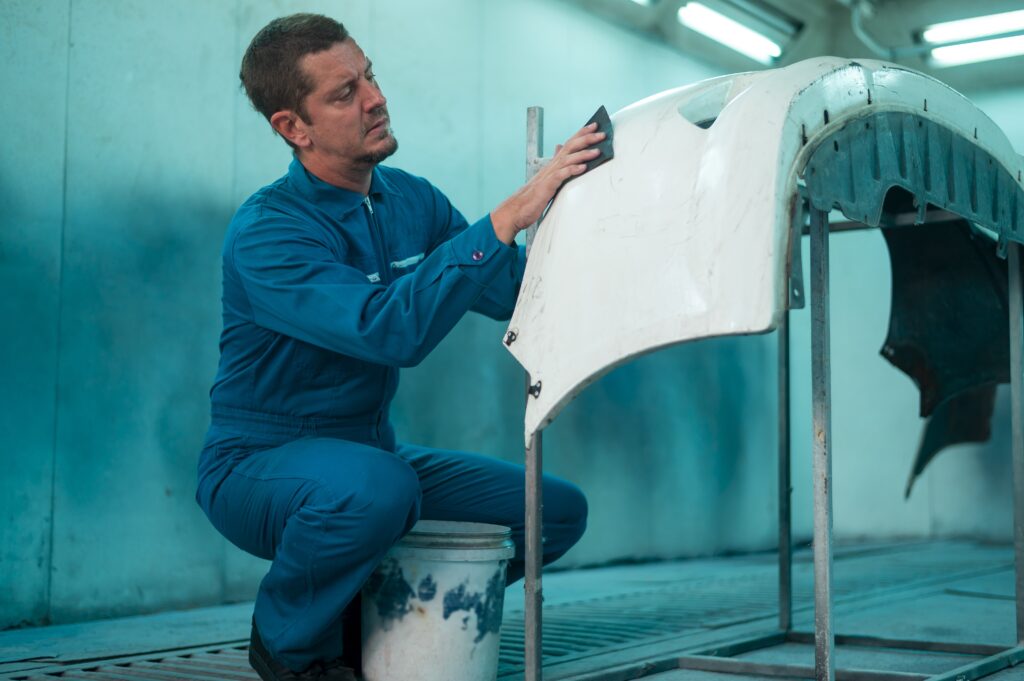 Technician performing car bodywork and paint repair at Roma Auto Body